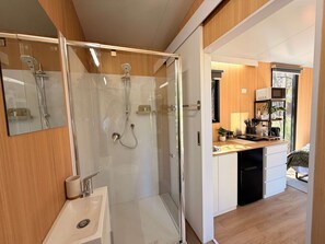 A modern bathroom with a glass-enclosed shower, a sink, and a mirror.