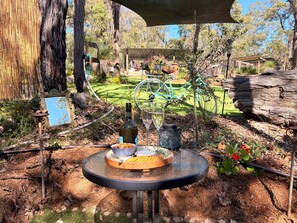 An outdoor dining area with a round table, a bottle, a glass, and a bowl of snacks.