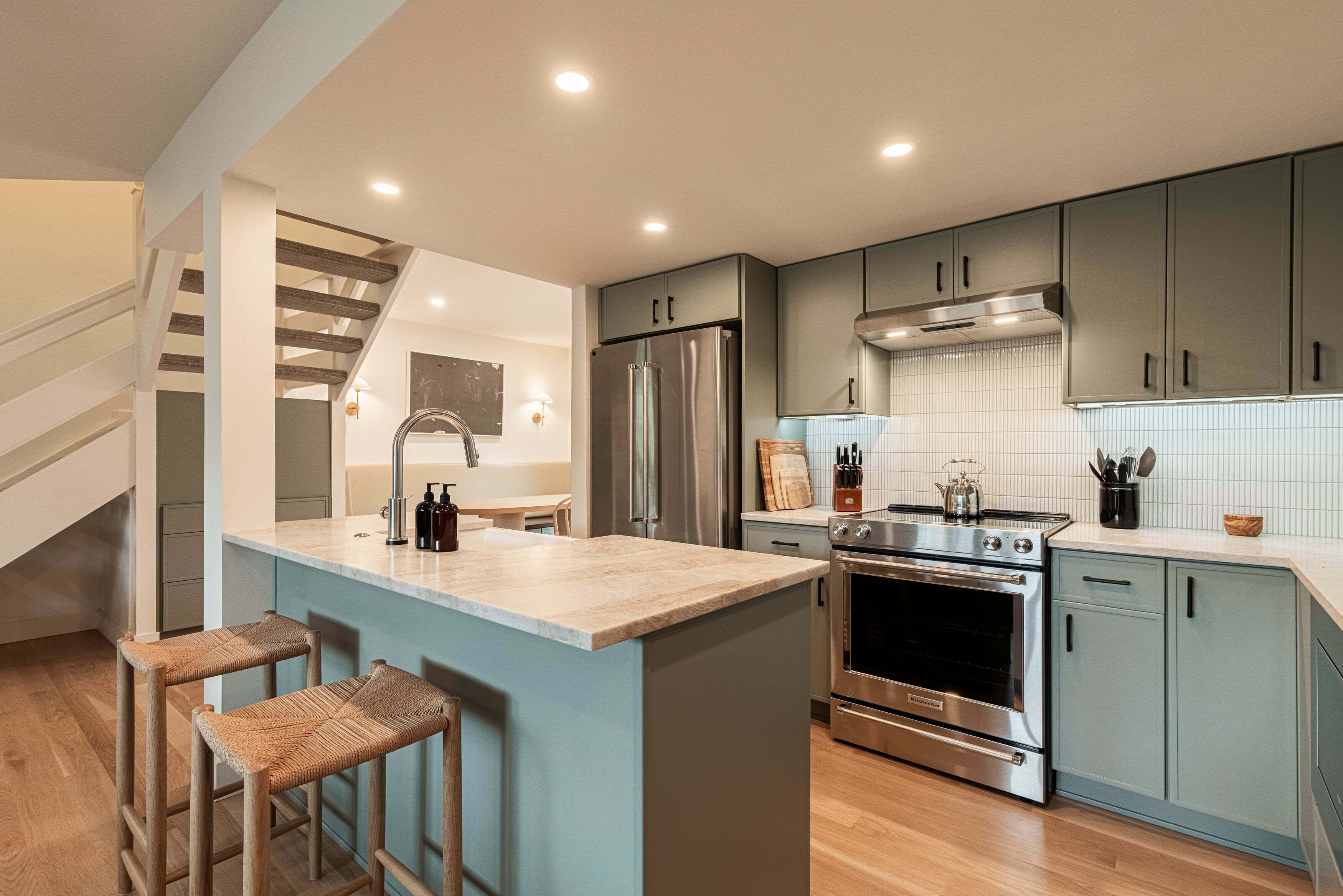 A modern kitchen with a central island, stainless steel appliances, and light blue cabinetry.