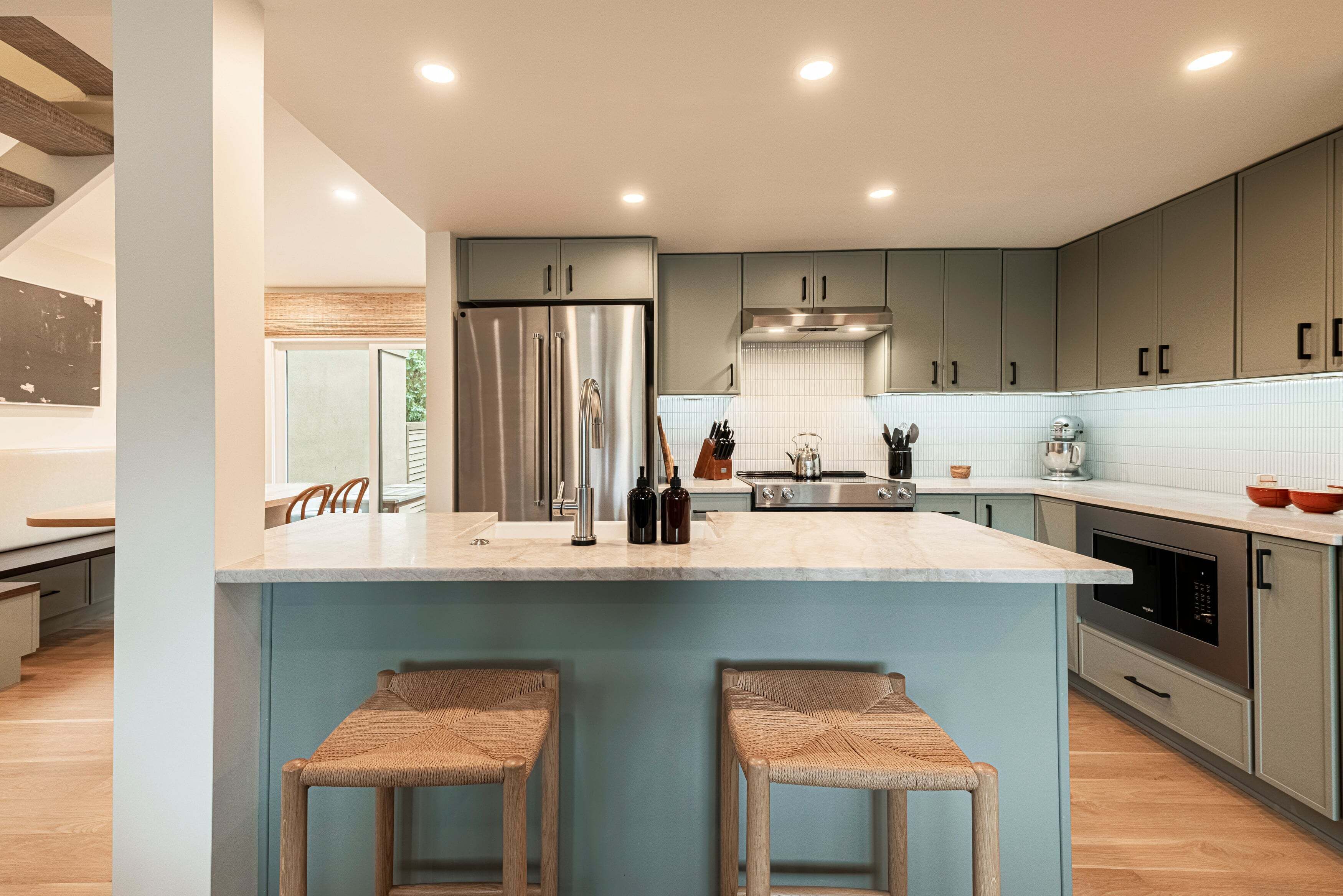 Une cuisine moderne dotée d’un îlot central, d’appareils électroménagers en acier inoxydable et de meubles de couleur claire.