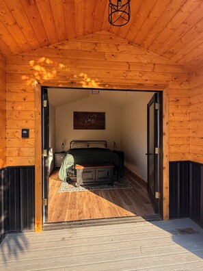 Un interior de madera con una cama, un letrero que dice 'Relax' y una puerta que da a un espacio exterior.