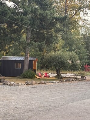A cabin with a small porch, a red chair, and a table.
