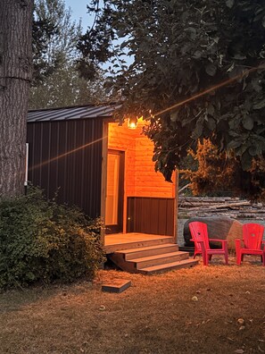 A small wooden cabin with a porch, steps leading up to the entrance, and two red chairs outside. - Cozy cabin getaway with private Green River access (Ravensdale)