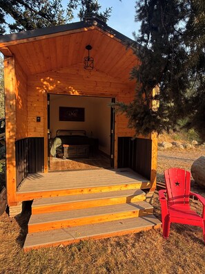 A wooden cabin with a bed, a sign that says 'Relax', and a red chair outside. - Cozy cabin getaway with private Green River access (Ravensdale)