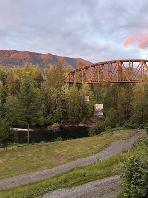 A bridge over a river with a forested area and mountains in the background.