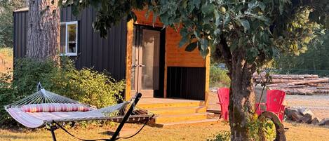 Une cabane en bois avec un hamac et une chaise rouge dans la cour.