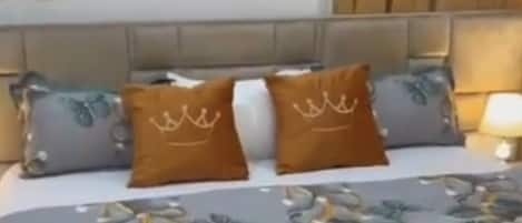 A hotel room with a bed, a headboard, a nightstand, and a lamp.