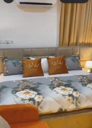 Een hotelkamer met een bed, een hoofdeinde, een nachtkastje en een lamp.