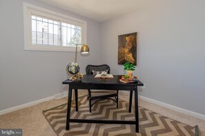 A room with a black table, a globe, a chair, a lamp, and a zebra painting on the wall. - Welcoming 3-bedroom house with Metro Access and Off Street Parking (Capitol Heights)