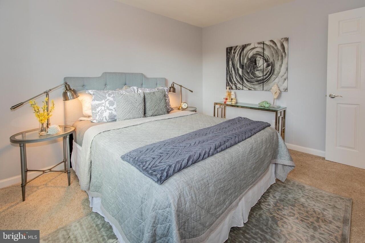 A bedroom with a bed, bedside tables, a lamp, a wall art piece, and a door.