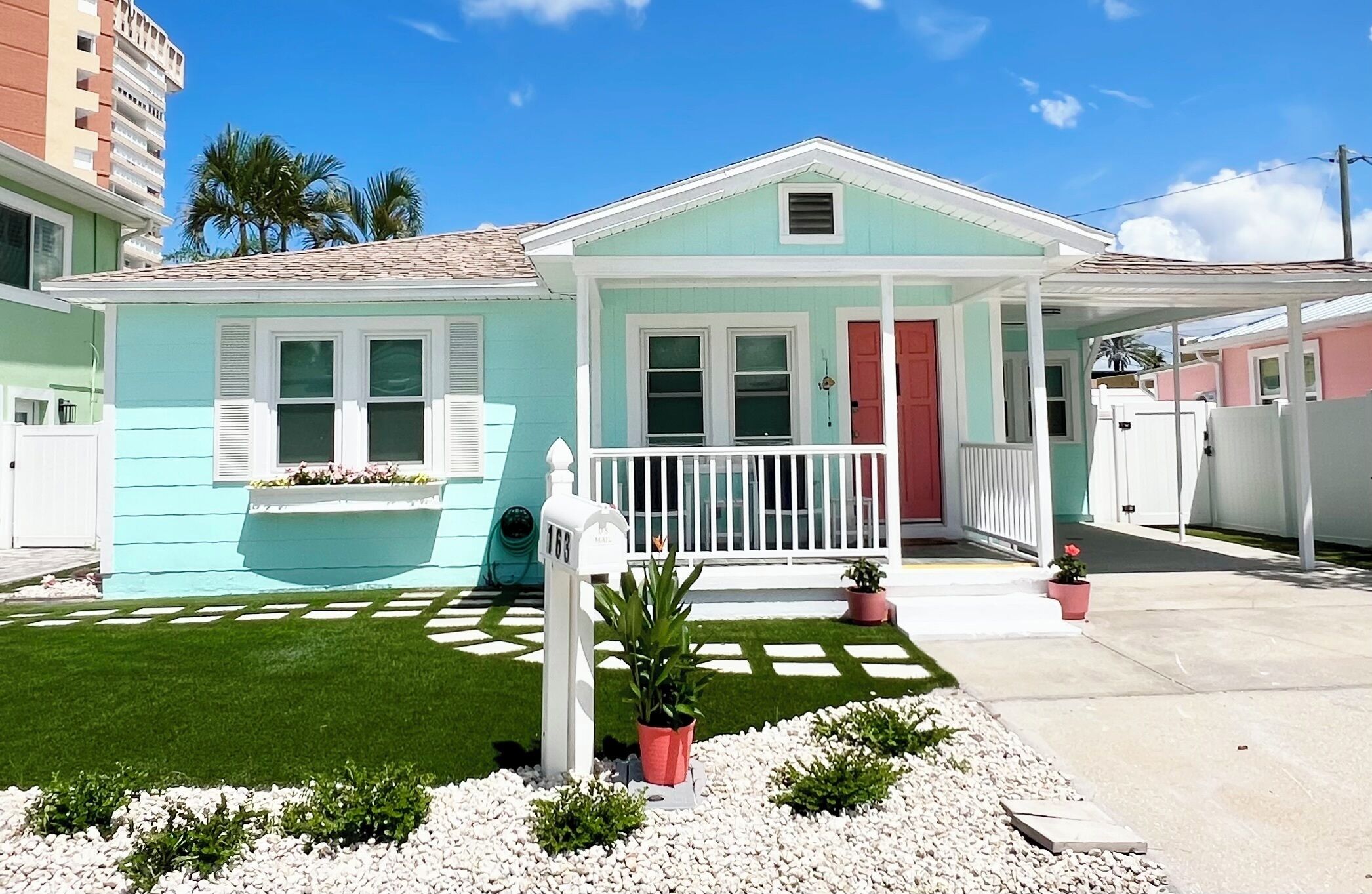 A two-story house with a porch, a mailbox, and a small garden.