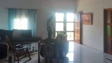 A room with a ceiling fan, a sofa, a dining table, and a window with curtains.