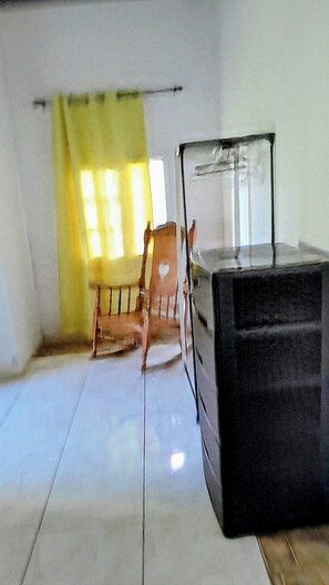 A room with a bed, a chair, and a window with a curtain.