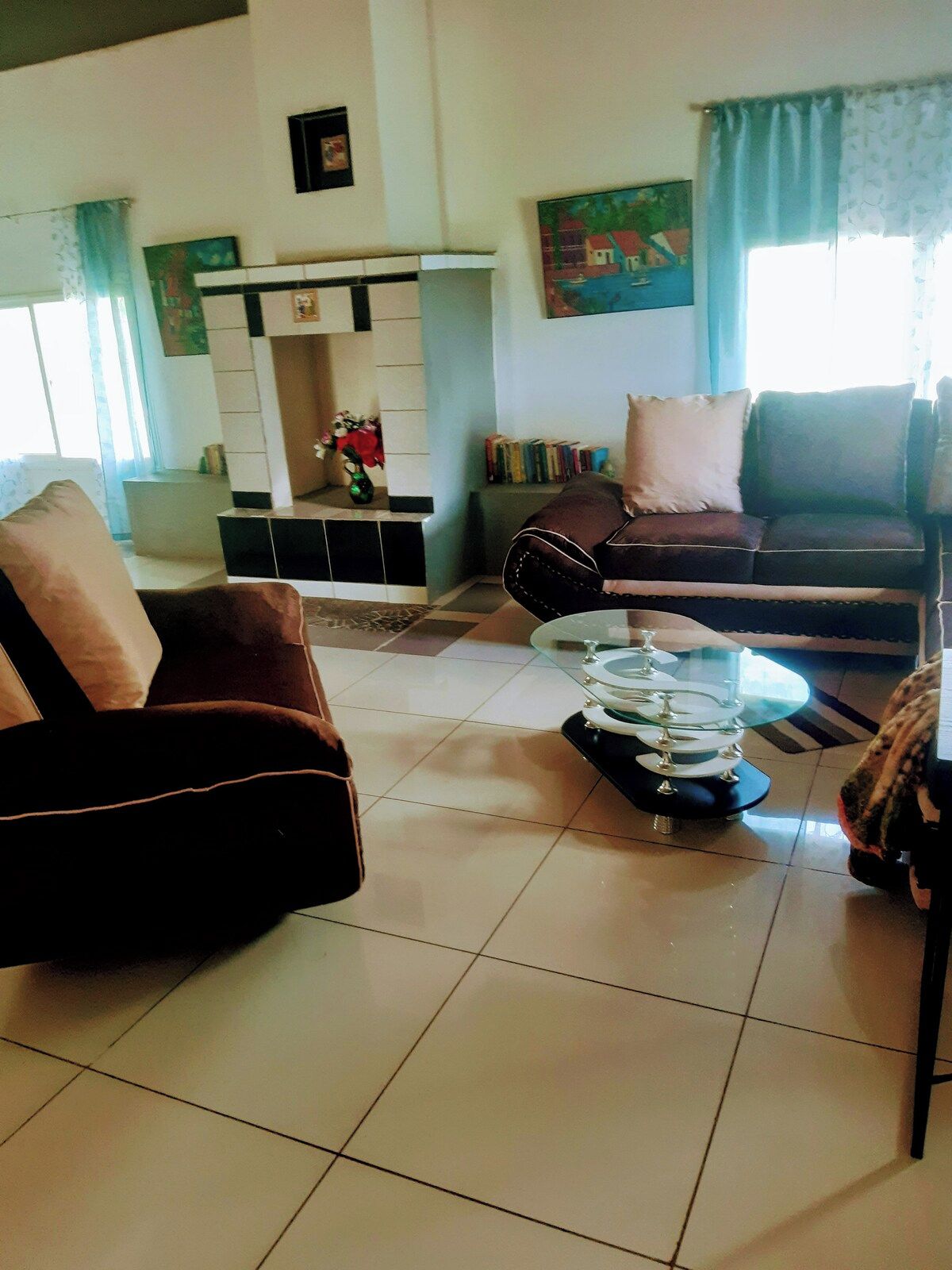 Una sala de estar con sofá, sillón y una mesa de centro. Hay una chimenea con repisa y estanterías.