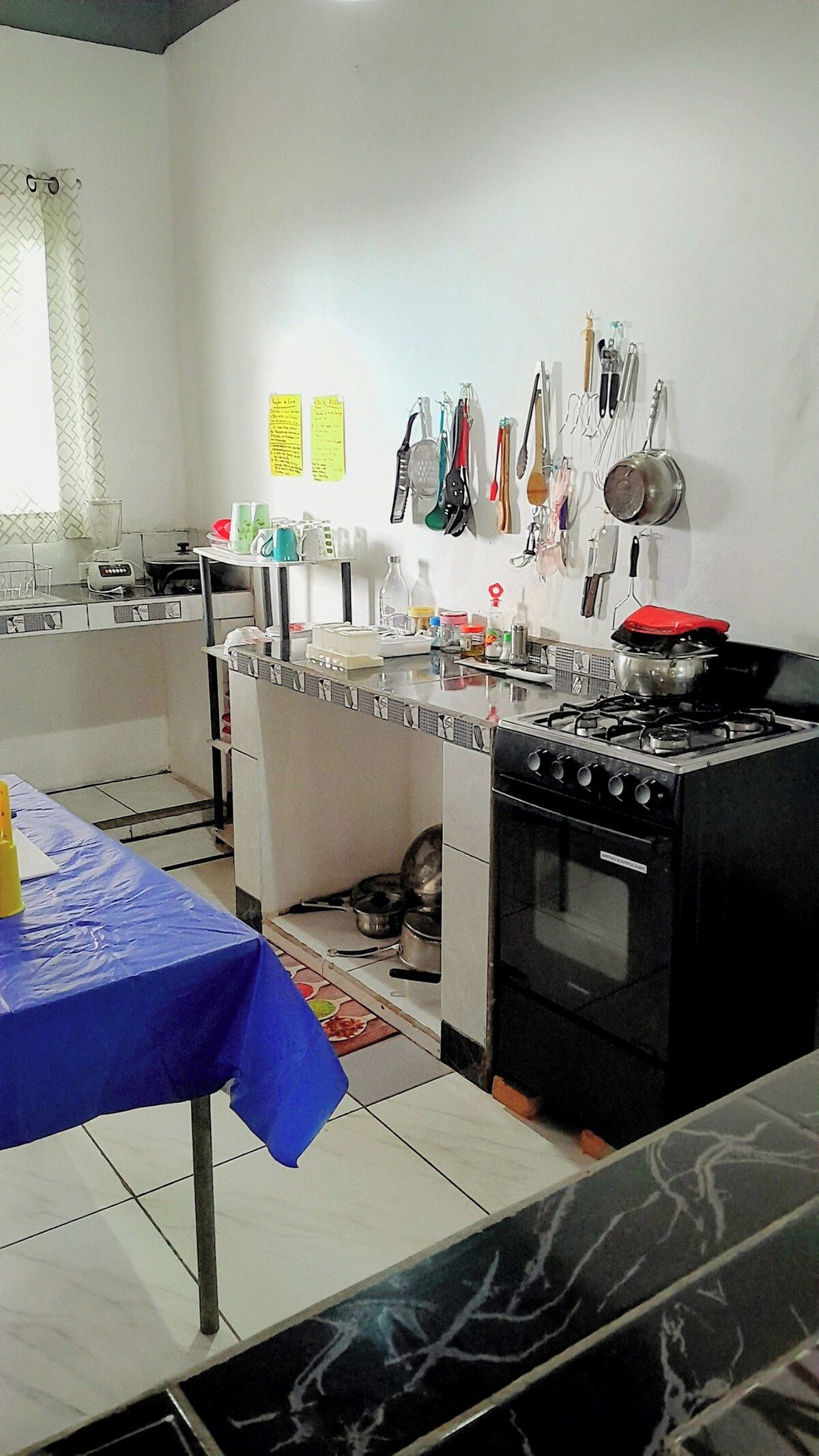 Cuina amb fogó, rentapesos i diferents utensilis penjats a la paret.