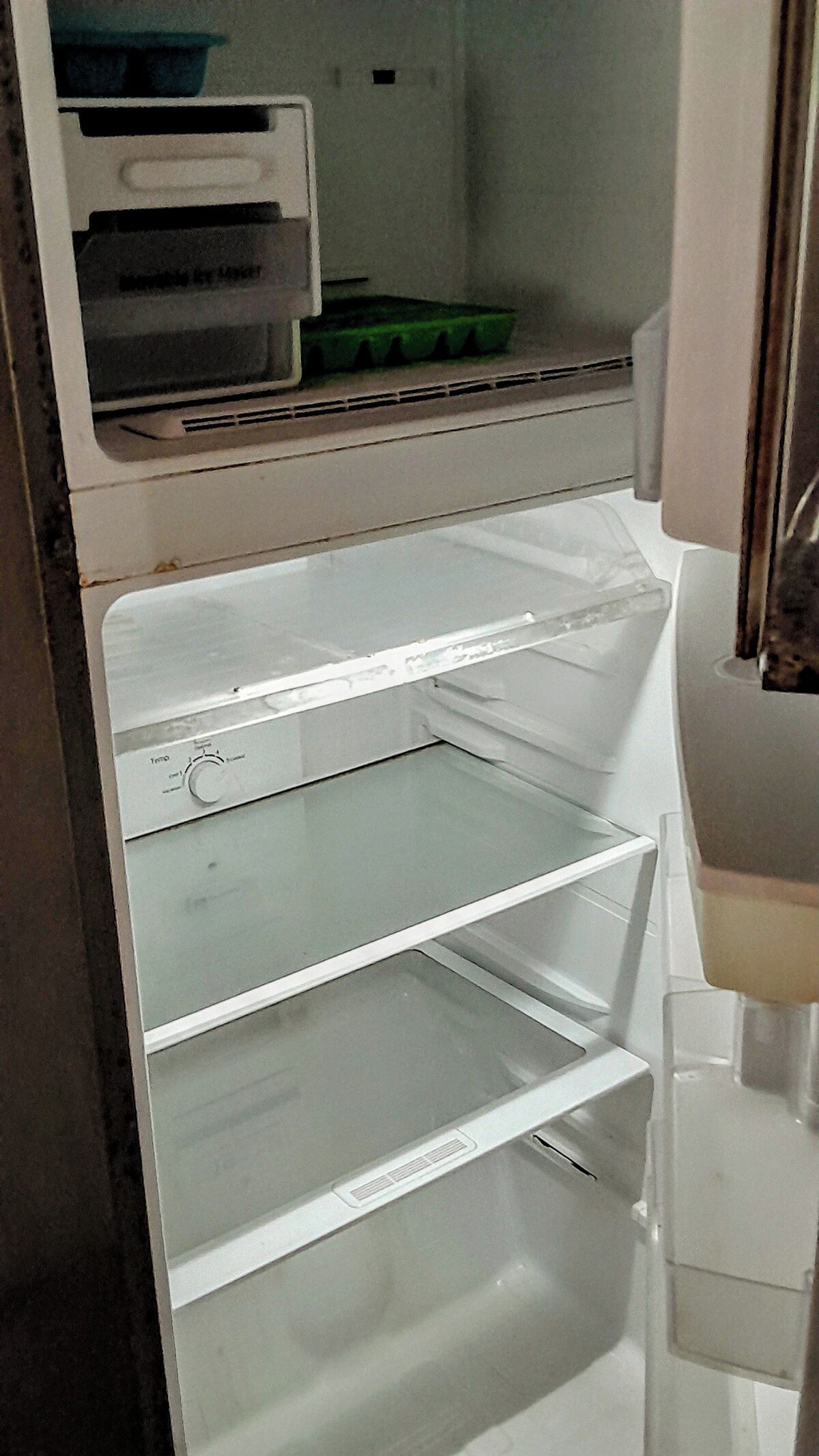 An empty refrigerator with multiple shelves and a freezer compartment.