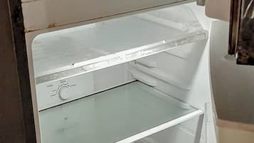 An empty refrigerator with multiple shelves and a freezer compartment.