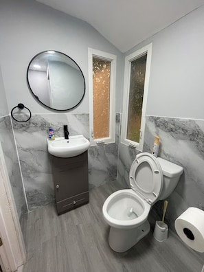 Een badkamer met toilet, wastafel, spiegel en een raam met decoratief folie.