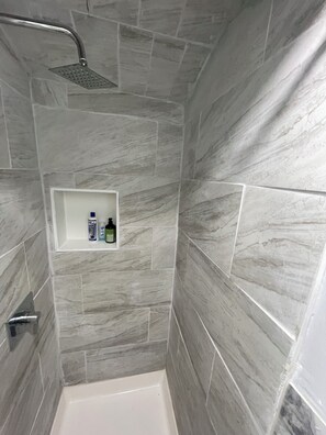 Un espace douche doté d’une étagère intégrée pour ranger les articles de toilette.