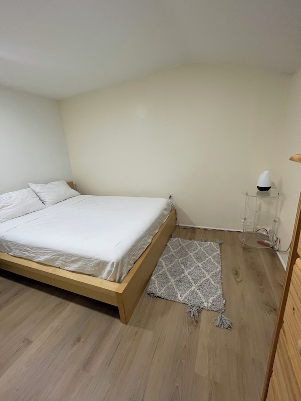 Een kamer met een eenpersoonsbed, een kleedje en een nachtkastje met een lamp.