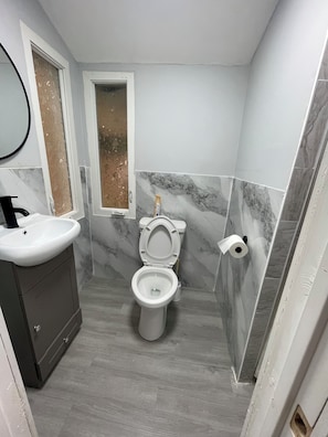 Een badkamer met toilet, wastafel en spiegel.