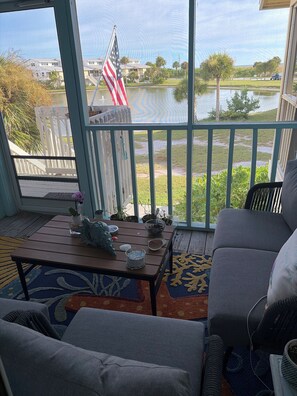 Un balcon donnant sur un lac, un drapeau et du mobilier d’extérieur.