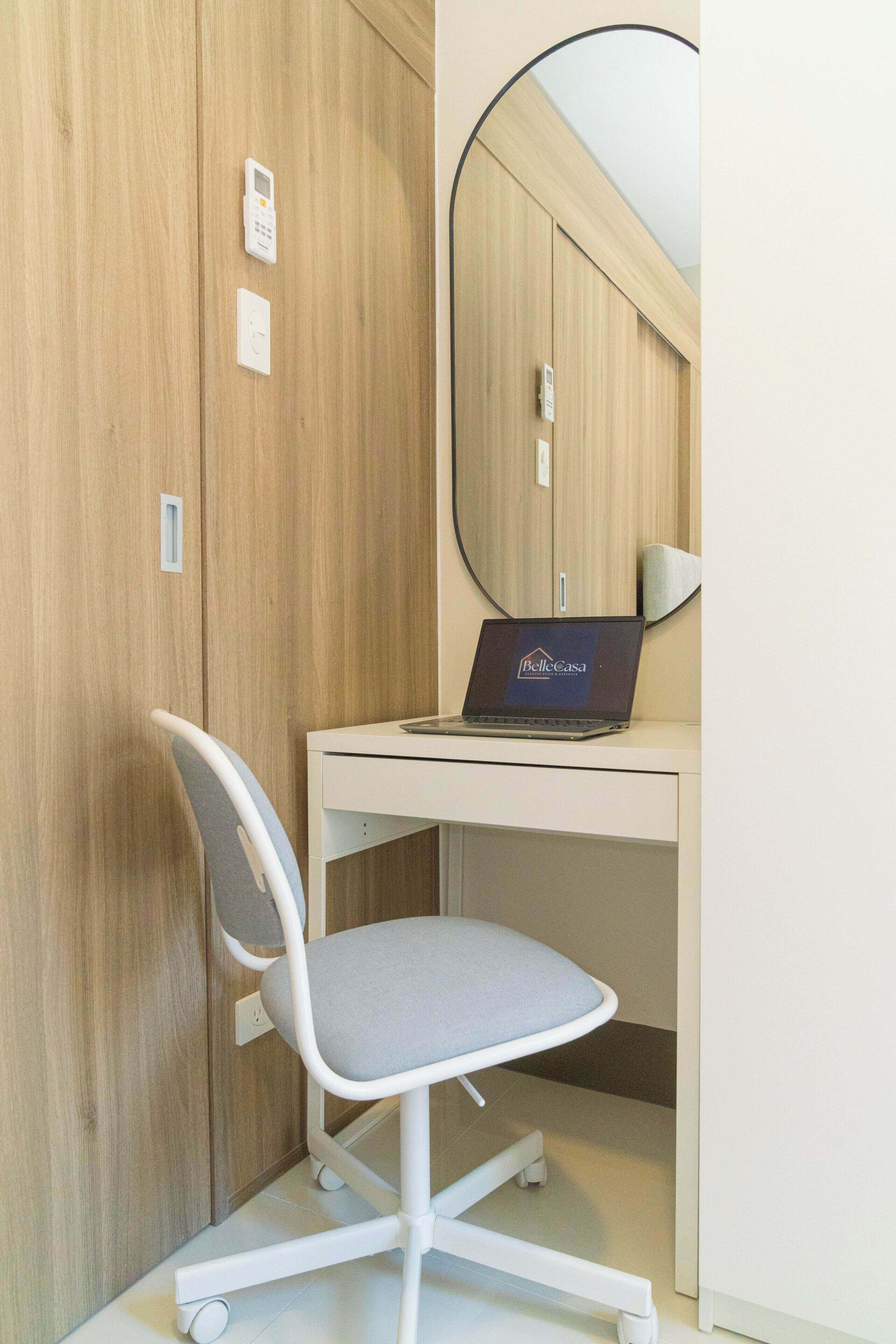 Un espace de bureau moderne comprenant un bureau, une chaise, un ordinateur portable et un grand miroir.