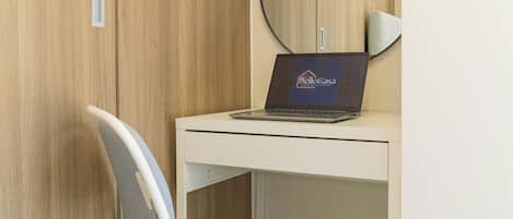 Un espacio de oficina moderno con escritorio, silla, laptop y un espejo grande.