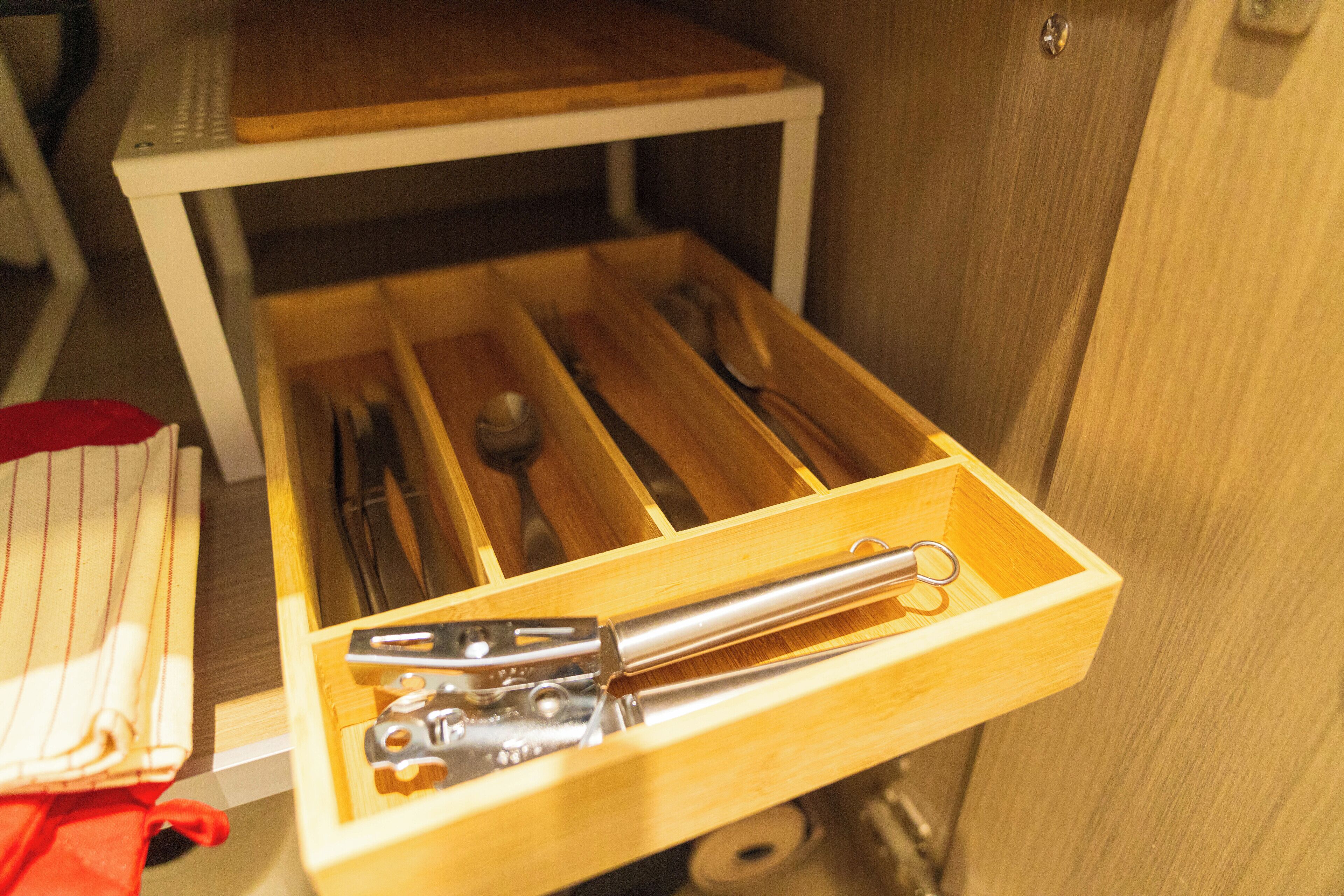 A wooden drawer with utensils inside.