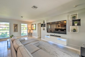 Ein modernes Wohnzimmer mit einem großen Flachbildfernseher, einer Couch und einem minimalistischen Design.
