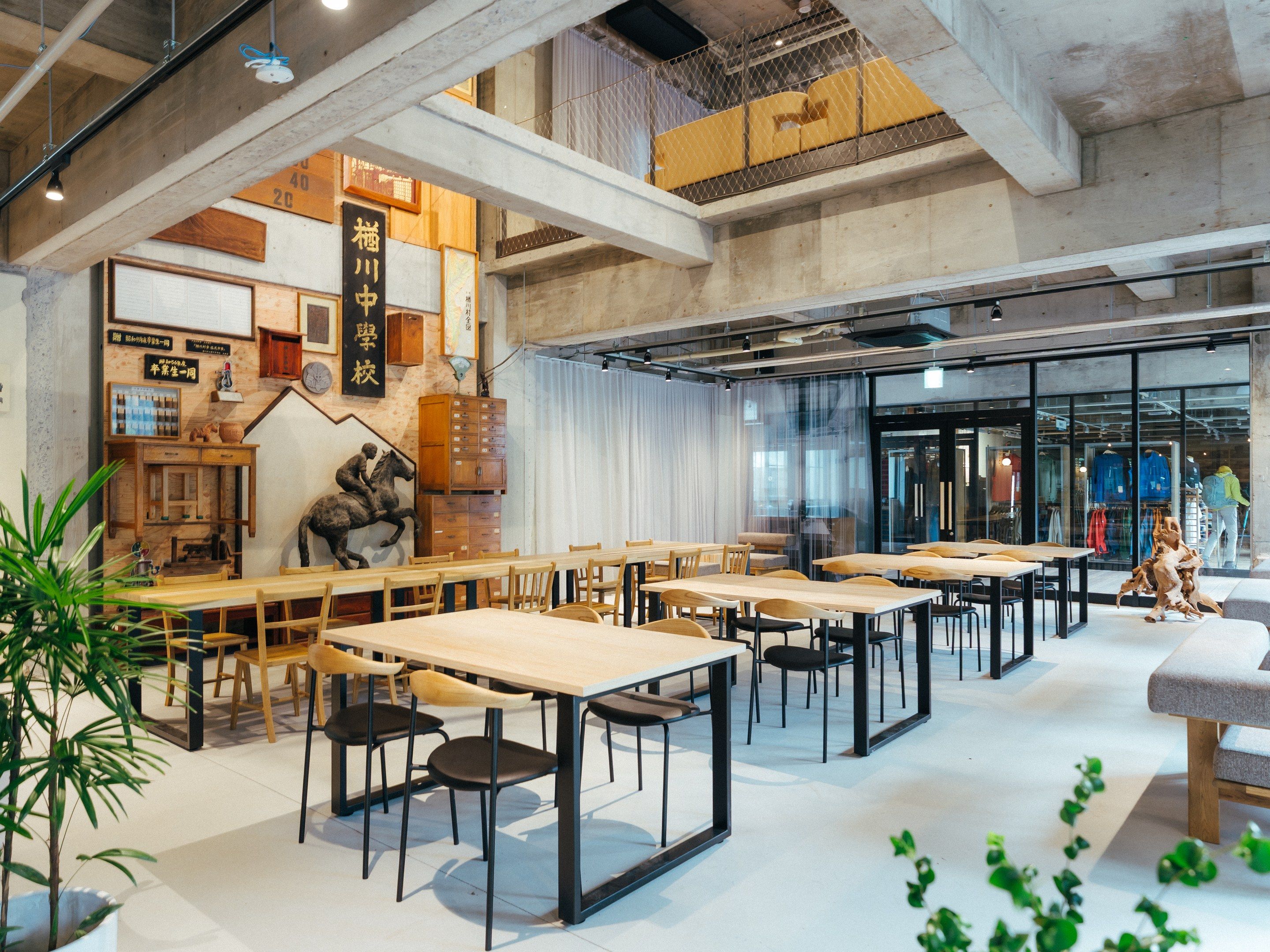A spacious cafe with multiple tables and chairs, wooden cabinets, and a large window overlooking the street.