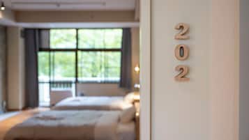 A bedroom with two beds, a large window, and a wall with the numbers '202' displayed.