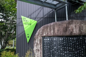 A building with a green triangular sign and a stone structure with Japanese characters.