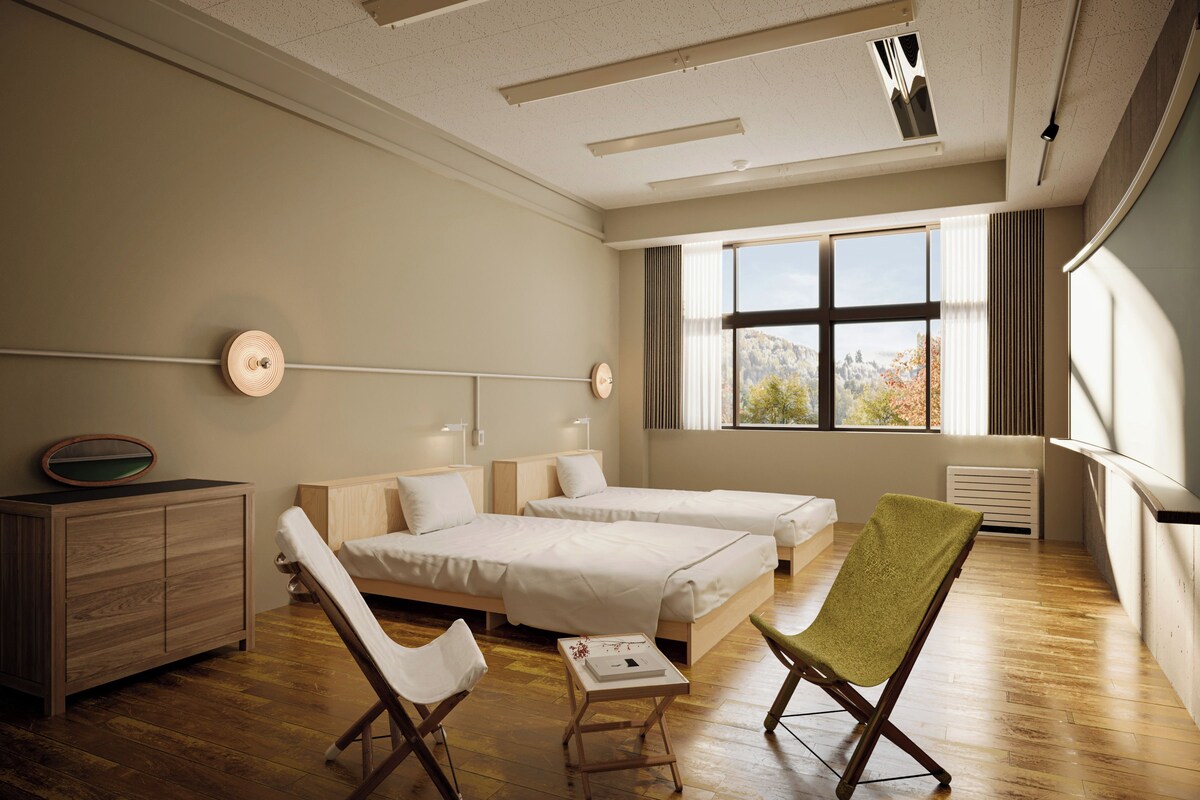 A hotel room with two beds, a desk, a chair, a dresser, and a window with a view.