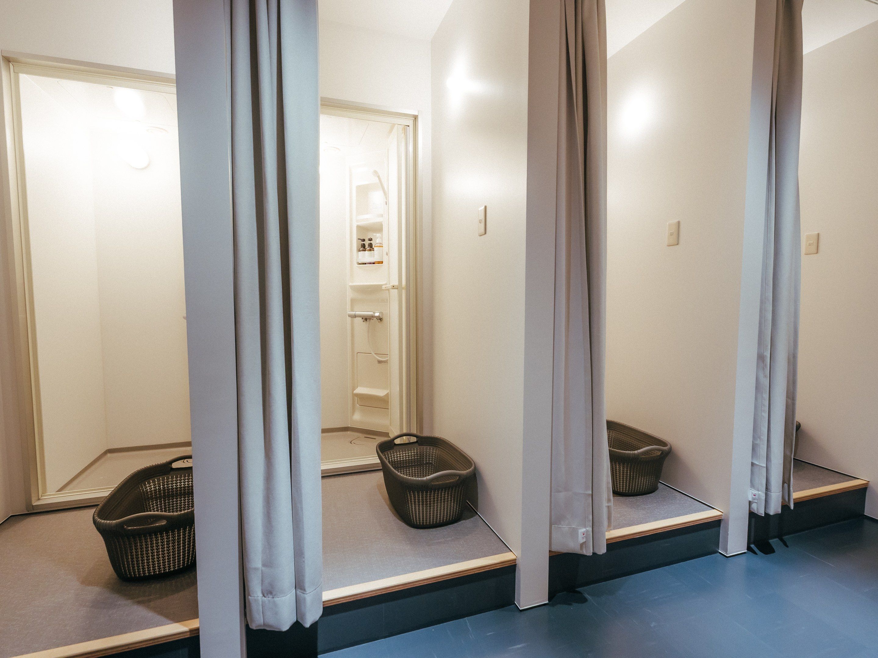 A bathroom with a shower, a mirror, and two baskets on the floor.