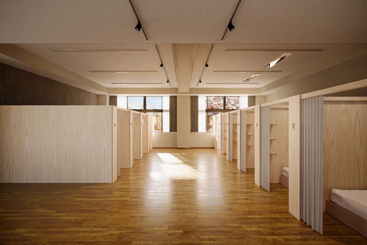 A hotel room with a wooden floor, a large window, and a view of trees.