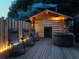 A wooden cabin with a log exterior, a sauna, and a hot tub.