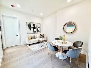 A modern living room with a white sofa, a round dining table, and two chairs.