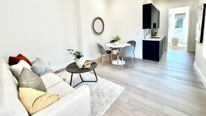 A modern living room with a sofa, coffee table, and a dining area with chairs and a small table.