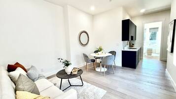 Un salon moderne avec un canapé, une table basse et un coin repas comprenant des chaises et une petite table.