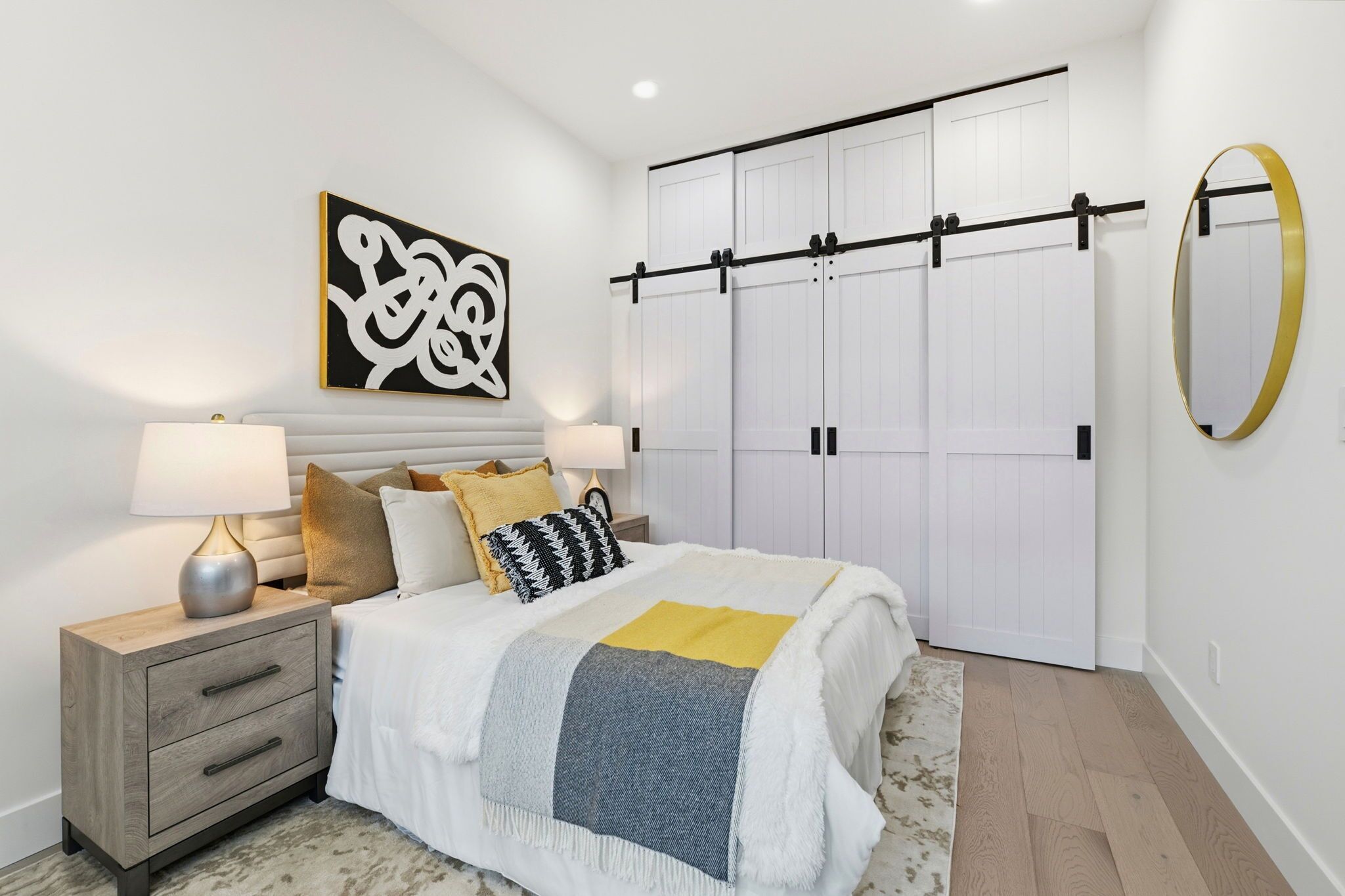A bedroom with a bed, nightstands, a large mirror, and a wardrobe with sliding doors.