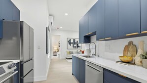 A modern kitchen with stainless steel appliances, a central island, and blue cabinetry.