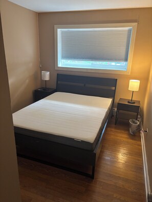 A bedroom with a bed, a window with blinds, a nightstand with a lamp, and a trash can. - Wonderful 2bedroom condo in Villa Park, walking distance to train station (Villa Park)