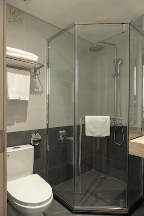 A modern bathroom with a glass-enclosed shower, a toilet, and a sink.