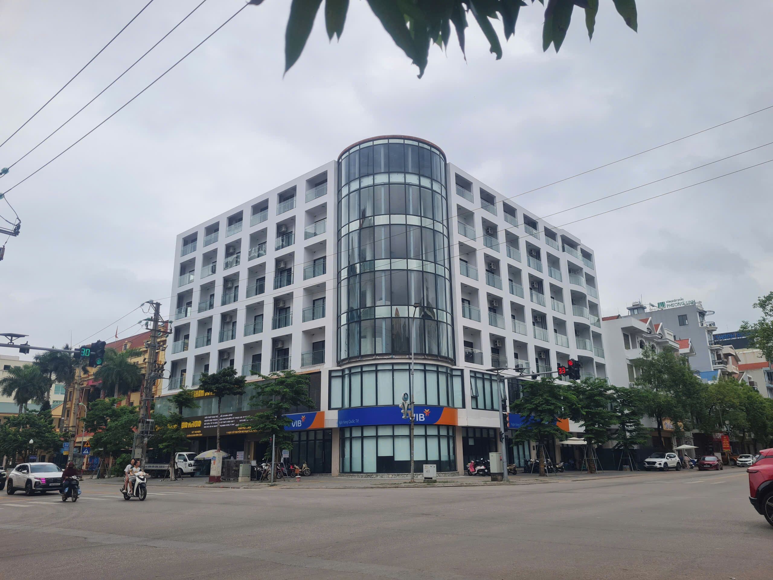 A multi-story building with a curved glass facade, surrounded by other commercial structures.