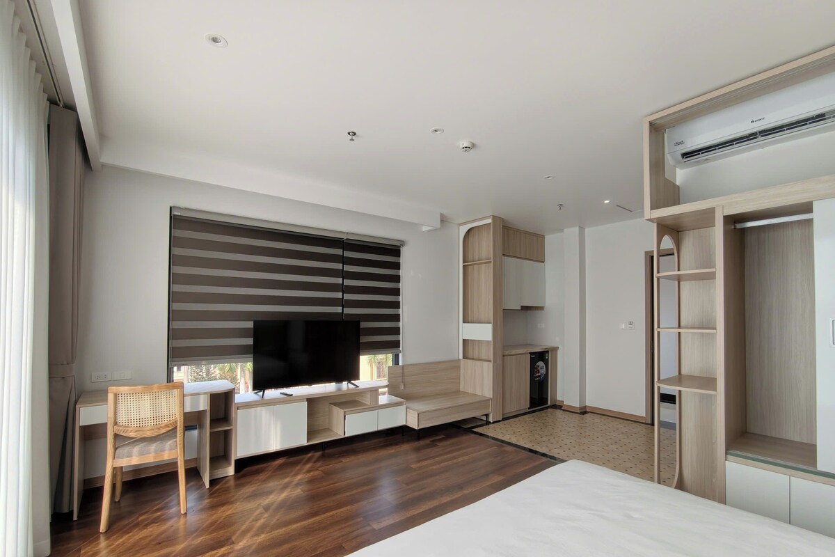 Een moderne hotelkamer met een groot bed, een bureau met een flatscreen televisie, een kledingkast en ingebouwde planken.
