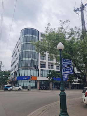 A modern building with a curved glass facade, a VIB sign, and a street lamp with directional signs.