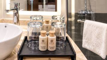 A bathroom with a sink, mirror, and shower. There is a tray with toiletries and a shaving kit.