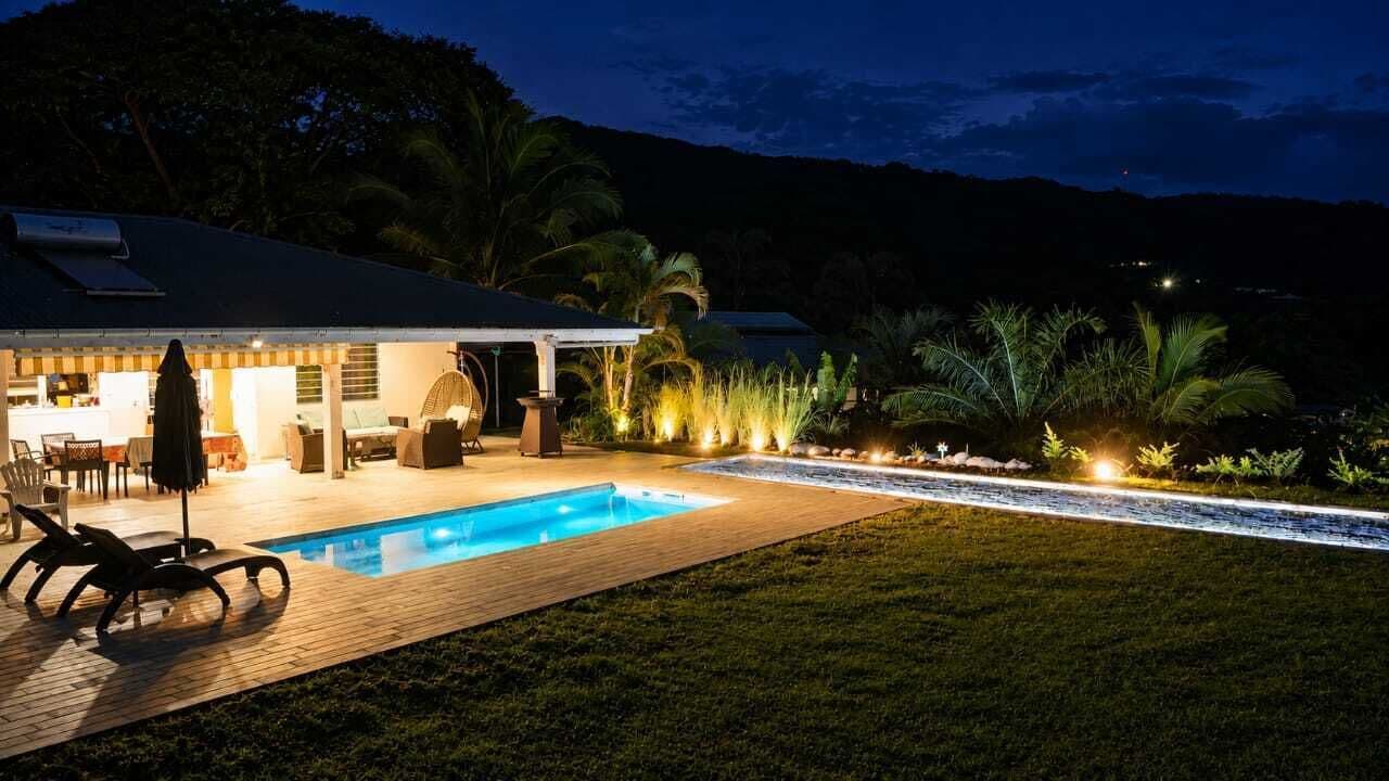 A poolside area with a covered seating area, a pool, and a view of the surrounding landscape.