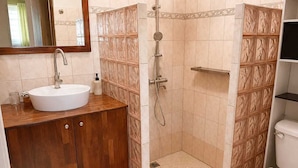 Un bagno con un mobile bagno in legno, un lavandino bianco, un box doccia e un water.